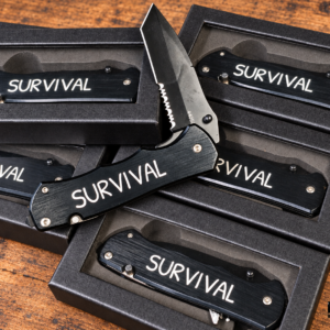 Lenwood Survival folding knife shown open with serrated blade, pocket clip, and Lenwood blade engraving on black presentation boxes.